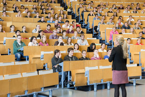 Eine Dozierende steht vor Studierenden in der Vorlesung im Hörsaal. 